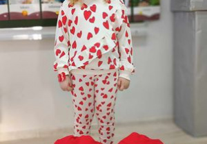 Dziewczynka w stroju w serduszka pozuje do zdjęcia z poduszką w kształcie serca