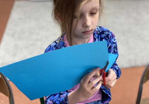 Dziewczynka wycina z niebieskiego papieru serduszko
