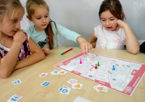 Dziewczynki grają w edukacyjną grę planszową.