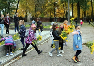 Dzieci składają kwiaty na mogiłach poległych żołnierzy.