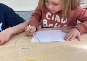 Dziewczynka maluje obrazek „magicznym atramentem” zrobionym z soku z cytryny